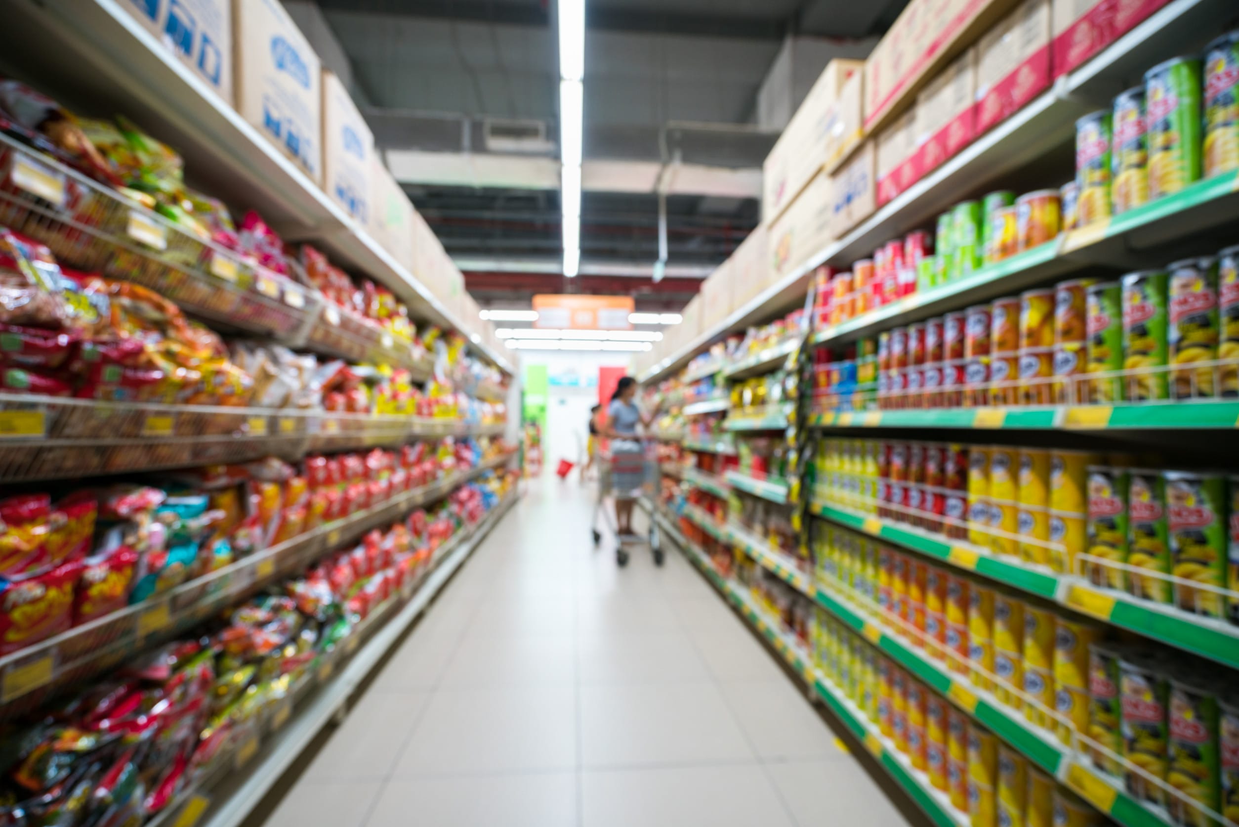 Supermarket blurred background with colorful shelves and unrecognizable customers Grocery Store Aisle