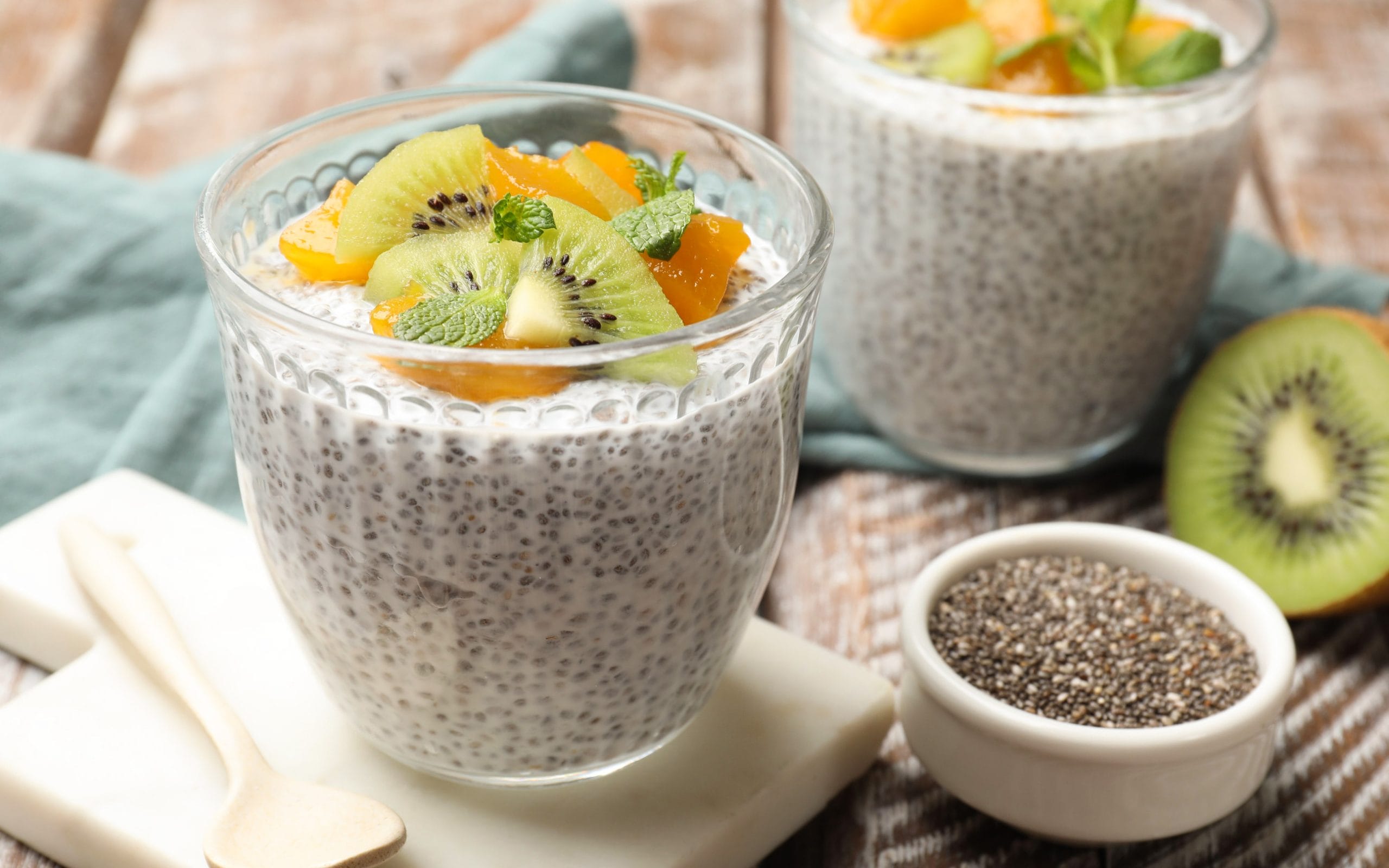 Delicious chia pudding with kiwi, peach and mint in glasses serv modern food trends