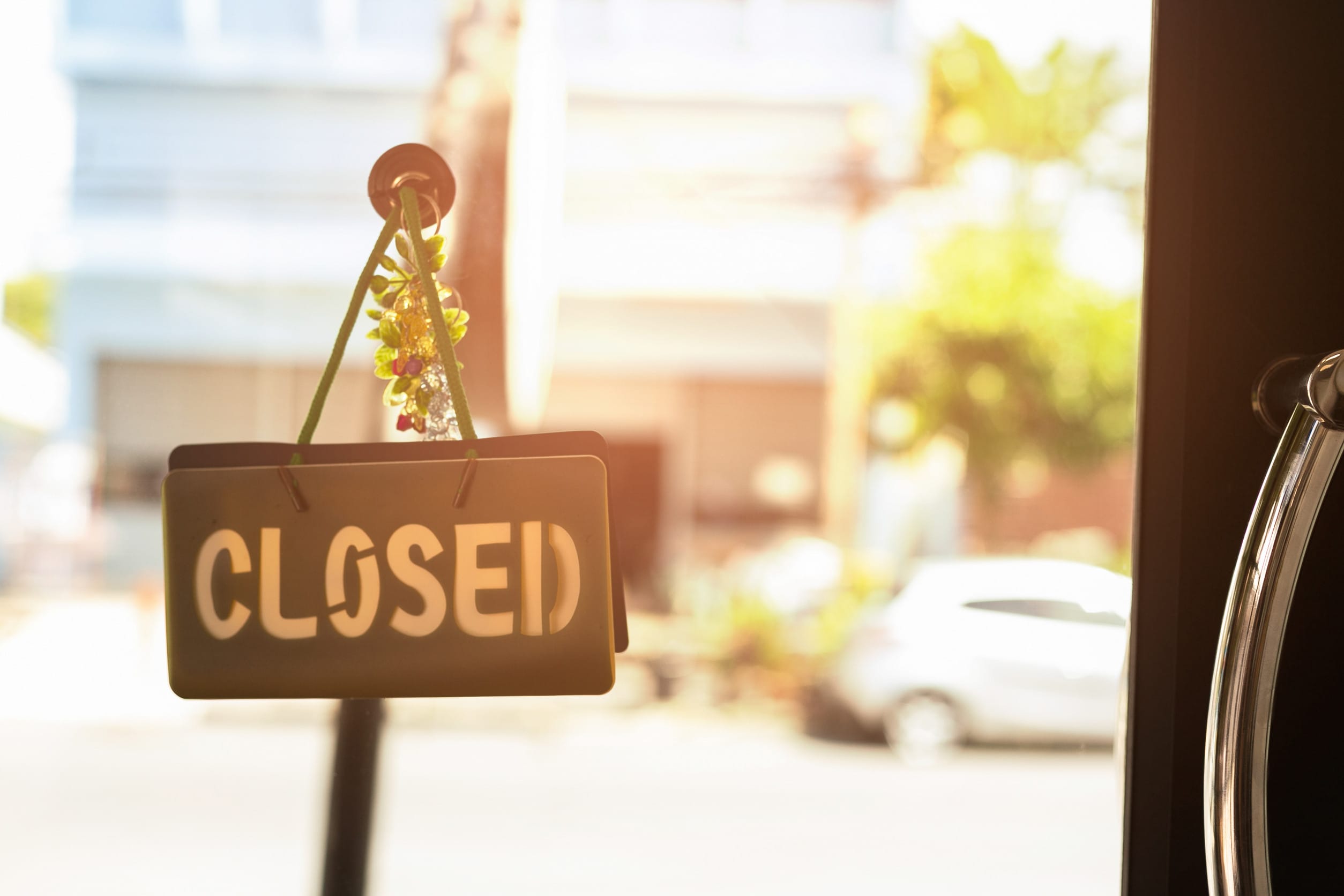 Closed sign hanging front of cafe with colorful bokeh light back abandoned retail chains