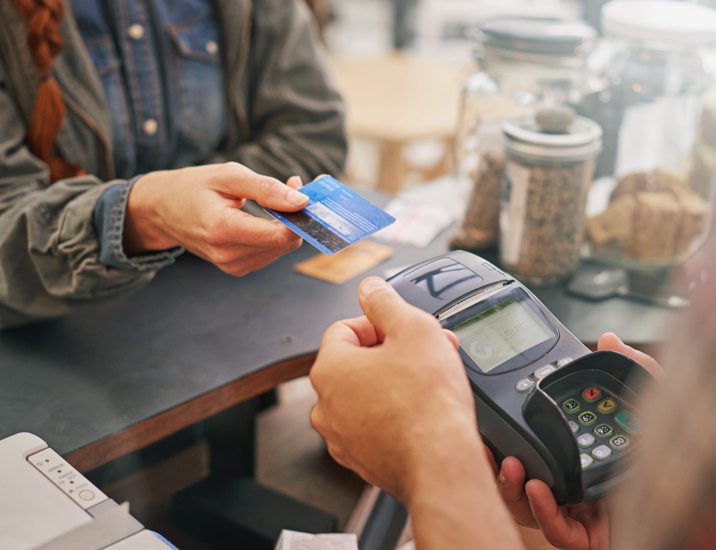 Credit card, debit machine and customer in cafe with hands of cashier for shopping, point of sale and checkout. Payment technology, bills and closeup of person paying for finance in restaurant store Discover 5% grocery store