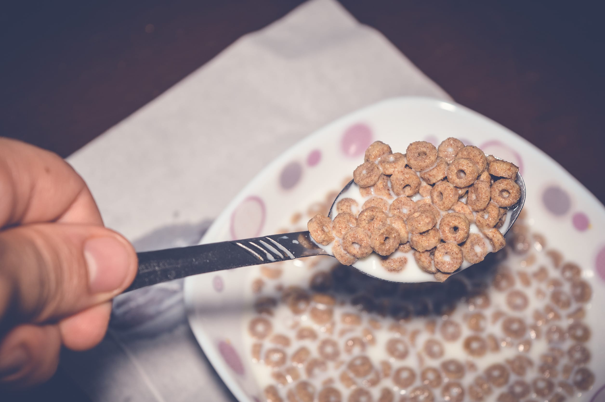 closeup of hand holding corn flakes with milk in a spoon lab tests